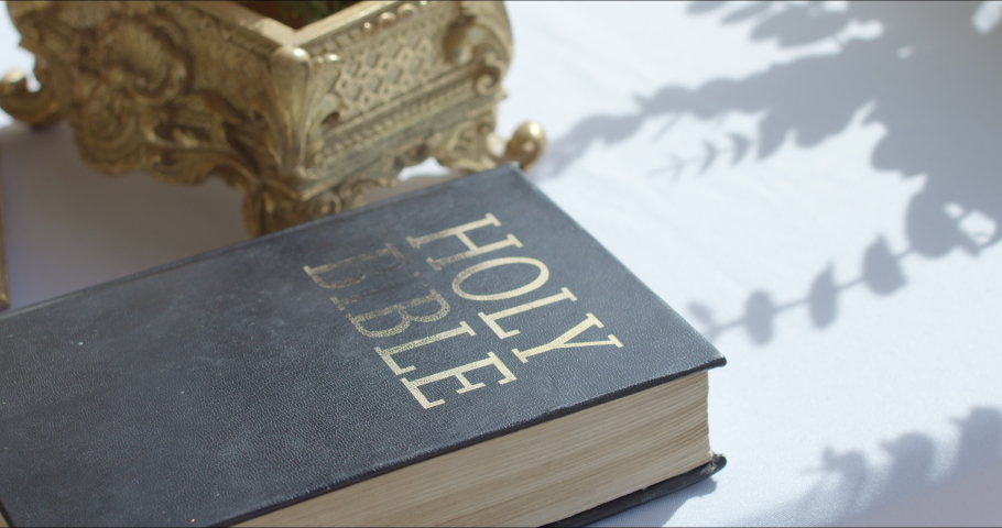 Green Christian bible with flowers in its design lies on a white table and will be used during a wedding