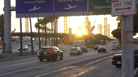 Los Angeles, California - United States - October 18, 2021: Static shot of cars going in and out of the Los Angeles International Airport entrance on Century Blvd. at sunset. 