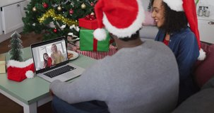 Happy african american couple on video call with female friend and daughter at christmas time. christmas, festivity and communication technology.