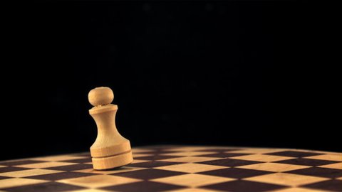 Super slow motion chess figure falls on the chessboard. On a black background.Filmed on a high-speed camera at 1000 fps.