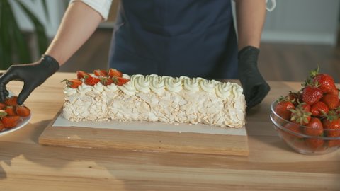 Close-up. The Pastry Chef Puts Fresh Strawberries on a Meringue Cake With Cream. Beautiful Cake Decoration With Cream and Strawberries.