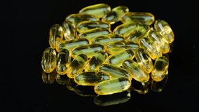 omega 3 gold fish oil capsules, rotation on black background, 4k vdo