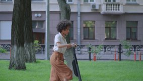 Beautiful woman with curly hair riding electric scooter in park, rental services - Powered by Shutterstock - Get 15% off with code: PIKWIZARD15