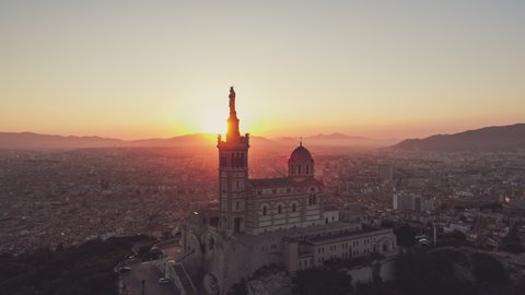 Establishing Aerial View Shot of Marseille Fr, Bouches-du-Rhone, Provence-Alpes-Cote d'Azur, France, heavenly sunrise, stroke of lights in lens, fast circling to the left