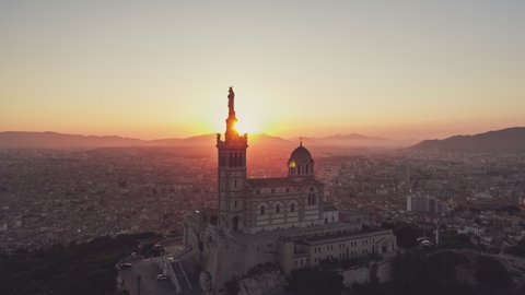 Establishing Aerial View Shot of Marseille Fr, Bouches-du-Rhone, Provence-Alpes-Cote d'Azur, France, heavenly sunrise, stroke of lights in lens, slowly circling to the right