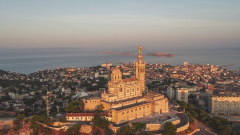 Establishing Aerial View Shot of Marseille Fr, Bouches-du-Rhone, Provence-Alpes-Cote d'Azur, France, 
Basilique Notre-Dame de la Garde in golden light, slow circling to the right with bay view