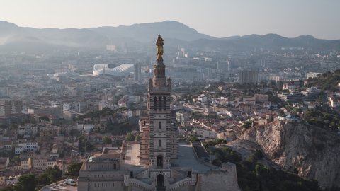 Establishing Aerial View Shot of Marseille Fr, Bouches-du-Rhone, Provence-Alpes-Cote d'Azur, France, Basilique Notre-Dame de la Garde, long paralaxe with mountain part of the city
