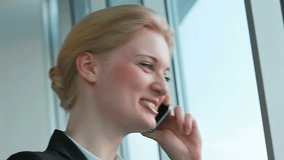 Pretty woman speaking on cellular phone in office