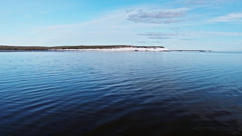 Water surface and faraway view of shore with gulls flying over the river. Yamal peninsula, Russia.