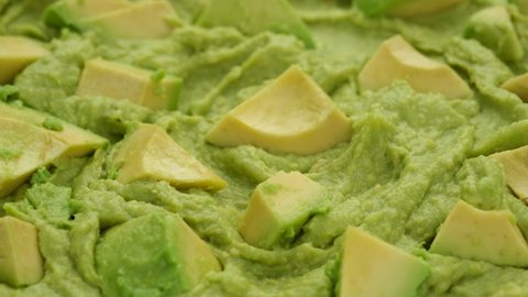 Fresh avocado puree and pieces close up, rotate. Fresh guacamole. Mashed avocado. Vegan food, clean eating, dieting concept. 4K UHD video
