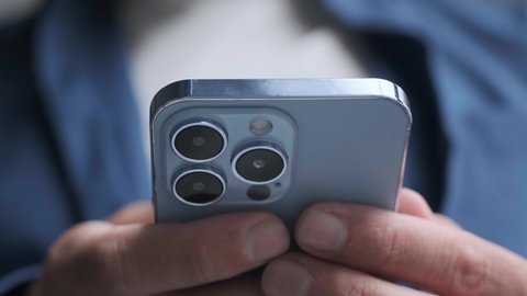 KYIV-20 OCTOBER,2021: Video of Iphone 13 Pro smart phone filmed in close up. Young man using modern mobile phone device in trendy Sierra Blue color with three lenses 