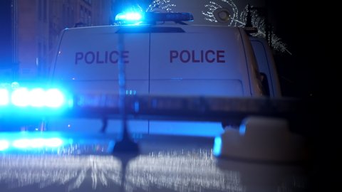 Emergency blue lights flashing on police car and van in the city at night