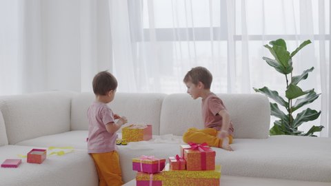 The Season of Giving concept. Two kids are opening Christmas gift boxes, playing at home Winter time, New Year presents and seasonal tradition - gift-giving.