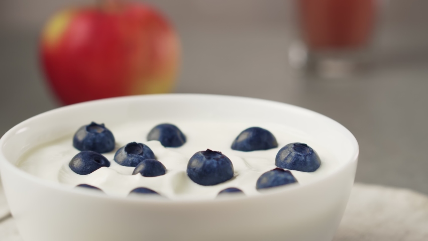 Hand picks up yogurt and blueberry with a spoon. Bowl of greek yogurt with blueberries.  Royalty-Free Stock Footage #1081173410
