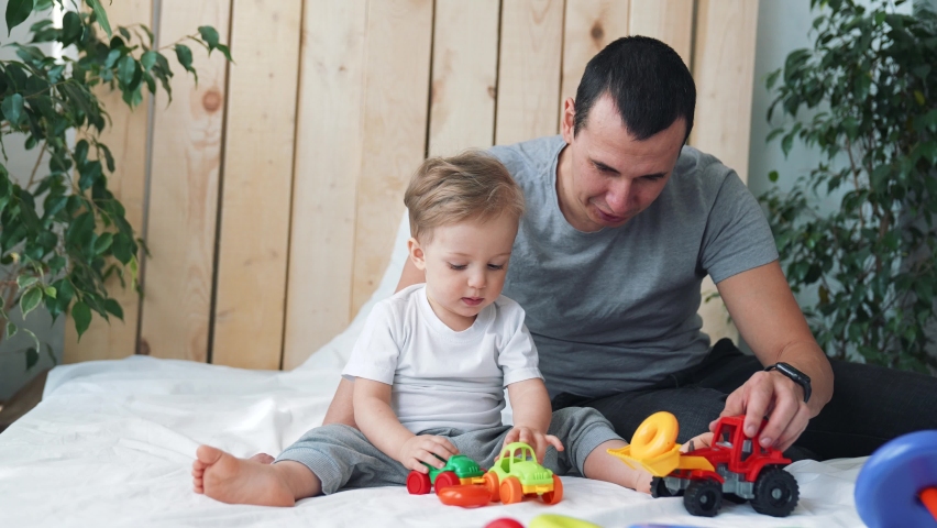 Happy family. Father and son are playing at home. Kid with dad plays with toy car. Child with father plays with toy car. Father day at home on couch. Family in room playing lockdown on bed.