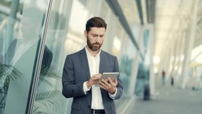 stylish bearded businessman in formal business suit standing working with tablet in hands on background modern office building outside. Man using smartphone or uses mobile phone outdoors city street - Powered by Shutterstock - Get 15% off with code: PIKWIZARD15
