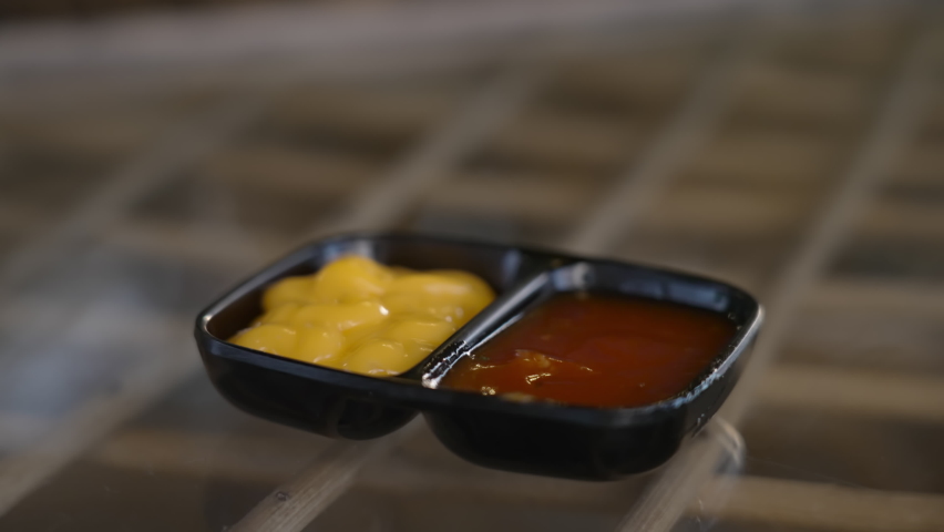 Close-up of a person dipping a Mexican tacos into a bowl of cheese sauce and scooping up the sauce. Typical of eating spicy Mexican dishes. There is a bowl of red ketchup and a sticky cheese sauce.