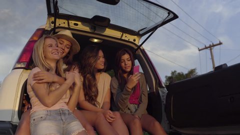 Group Of Teen Girls Watch Sunset From The Back Of An SUV, They Take Selfies Together (4K)