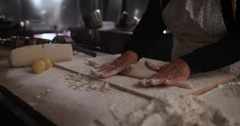 Woman kneads dough for fresh made gnocchi inside pasta factory