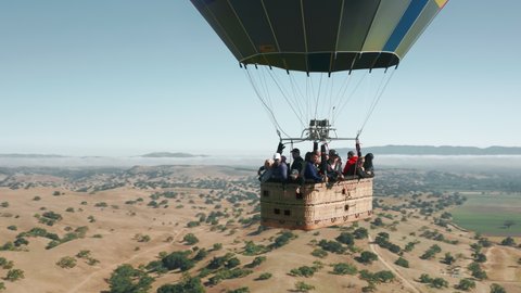 Solvang city area, California, USA, June 2019. Close up of colorful hot air balloon basket with happy excited people soaring above nature landscape USA. Scenic epic travel 4K tourism concept video