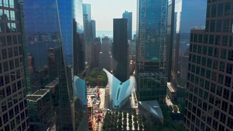 Drone flying close between modern architecture glass buildings business offices in New York downtown. Aerial above narrow urban street towards ground zero 911 memorial park and museum in Manhattan