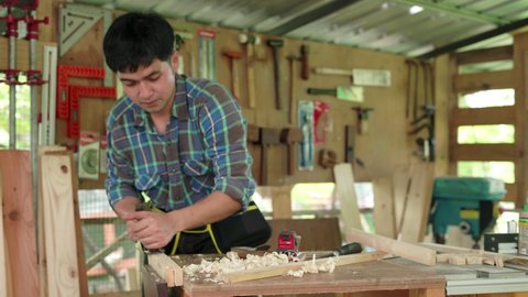 Asian man who owns a small lumber business is preparing wood for furniture production. carpenter is adjusting the surface of the wood to the desired size. Carpenter concept and small business owners.