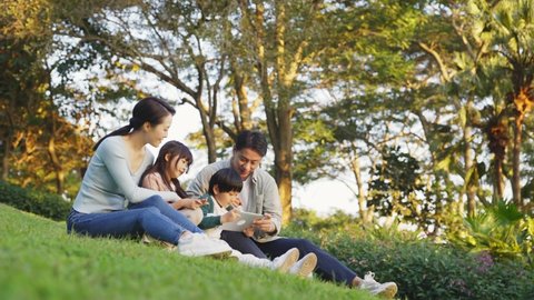 asian family with two children relaxing outdoors in city park