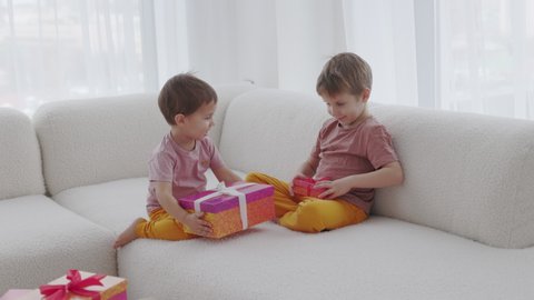 The Season of Giving concept. Two kids are opening Christmas gift boxes, playing at home Winter time, New Year presents and seasonal tradition - gift-giving.