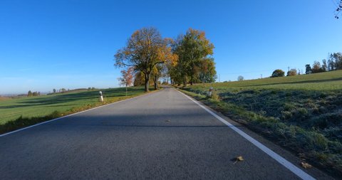 POV view of fall autumn landscape from car, fall colored trees in countryside landscape with blue sky in sunny day.