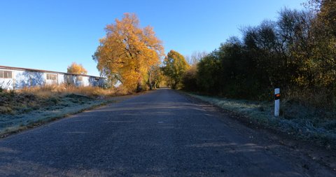 POV view of fall autumn landscape from car, fall colored trees in countryside landscape with blue sky in sunny day.