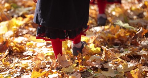 Slow motion of yellow autumn leaves rustle under the children boots