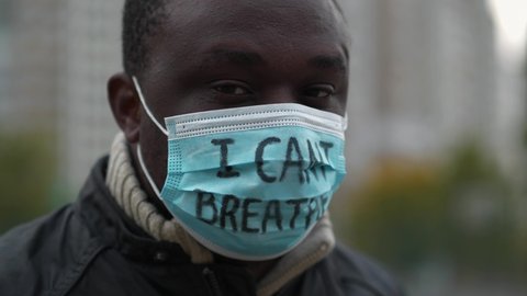 African american man activist in medical mask with an inscription I CAN'T BREATHE looks at camera and closed eyes. Black Lives Matter, BLM, racial discrimination, mass protests in USA, Slow Motion