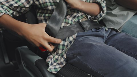 Midsection shot of unrecognizable boy in casualwear fastening seat belt before bus ride