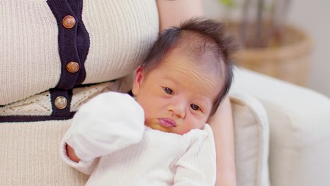 Newborn baby hiccups after feeding milk in mother arm.Asian newborn over feeding and swallow air frequently gets hiccups.Newborn Baby Health Care Concept