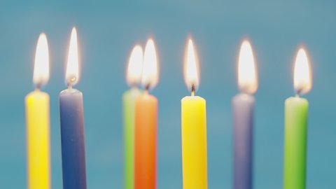 Blow off colorful birthday candels isolated on blue background shot in 4k super slow motion