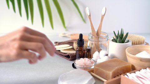 Natural bathroom and home spa tools. Zero waste sustainable concept. Woman hands drop in homemade DIY beauty products in reusable bottles on white background. Bamboo toothbrush, soap bar, cotton pads