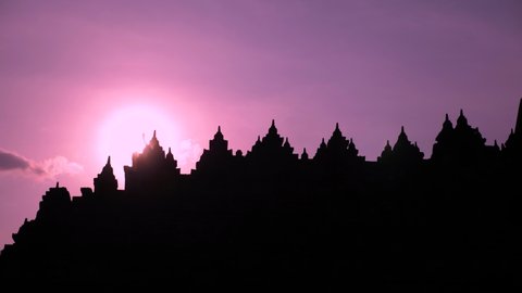Sunset at Borobudur temple in Java island, Indonesia. The beauty of Buddhist Temple Borobudur. 4K Silhouette of Mahayana Buddhist temple architecture in Magelang. UNESCO Complex close to Yogyakarta.