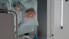 Vertical video: Doctor doing consultation with retired patient for healthcare in hospital ward. Medic talking to sick woman while nurse giving support for medical examination and recovery. Medical
