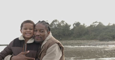 Father and toddler looking at camera on beach holiday