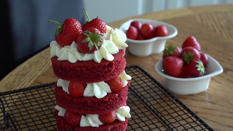 Caucasian woman hand decorates mini cake red velvet. Decorate with a mint leaf . The process of making a dessert. Decorating and cooking dessert cake red velvet.