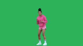 Young woman table tennis player happy to win raising his hands up over green background. African american girl wearing pink hoodie and shorts hits ball. Chroma key. 4k raw video footage