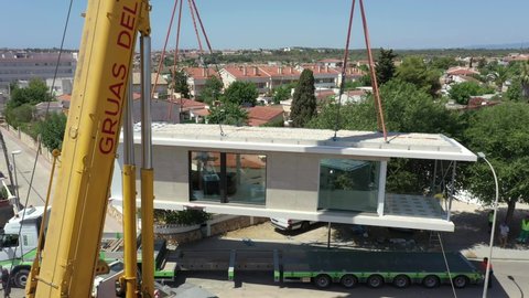 Barcelona , Spain - 07 24 2021: Close up of a large crane lifting a new home off the lorry to put in place. 