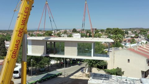 Barcelona , Spain - 07 24 2021: Impressive large crane lifting modular homes from the delivery lorry. 