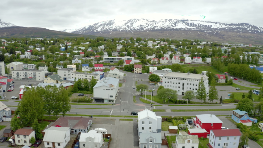 Flight across city of Akureyri - Iceland. From waterfront towards mountains. Low traffic Iceland Cityscape. Hlíðarfjall in background,