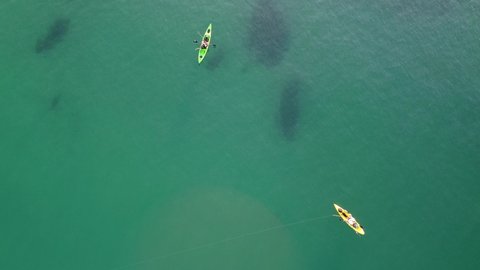 Two kayakers fishing, trolling fishing drone aerial view in mediterranean sea. Fisherman trolling in kayak at Spanish coast. Kayaker trolling and fishing at sea in his canoe.