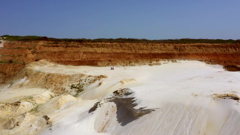 A romantic couple walk on white sand in a beautiful red canyon in the middle of nature. Aerial shot of people resting along the edge of a sand dune in the desert
