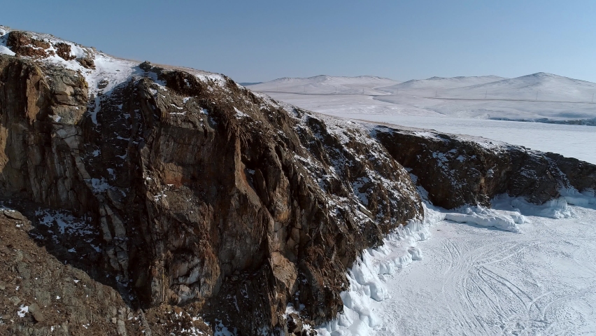 Aerial over the rocky cliff at lake Baikal. Winter landscape of frozen Baikal. Popular tourist spot