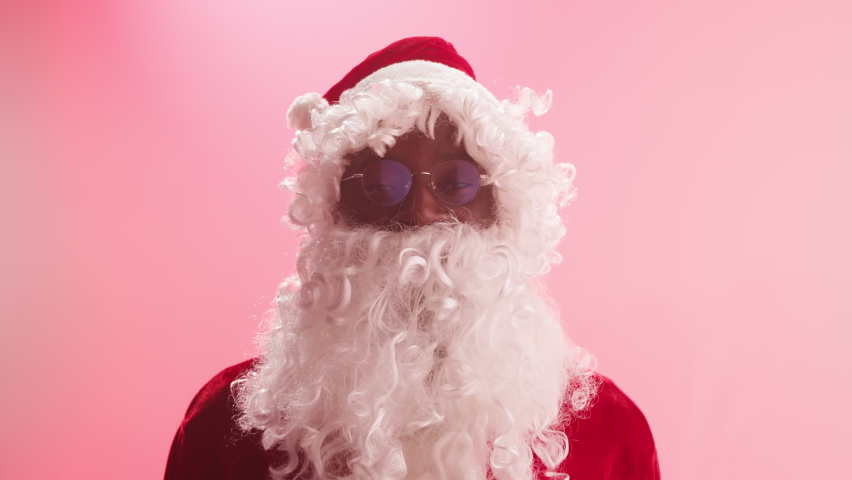 Happy Santa Claus portrait. Smiling african american man in christmas costume of santa close-up, looking in camera. Cheerful st Nicholas posing on red background. New year time concept.