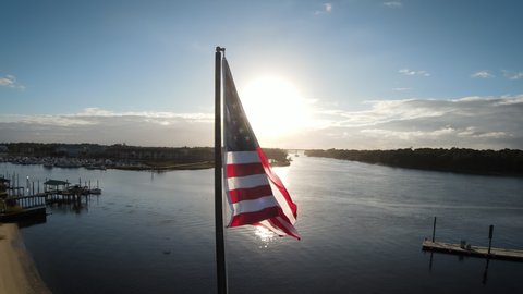The American flag flies at dusk in a coastal town.
