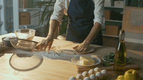 An Experienced Chef Sprinkles the Dough with Flour and Rolls it out with a Rolling Pin. Preparing Dough According to Traditional Recipes an A Modern Kitchen. Business and Baking Concept. Close-up.